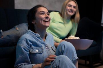 filmy na babski wieczór dwie uśmiechnięte kobiety oglądają film