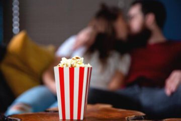 film na romantyczny wieczór oglądane przez całującą się parę z popcornem na pierwszym planie
