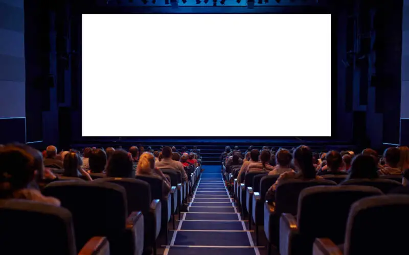 pełna sala kinowa z białym ekranem