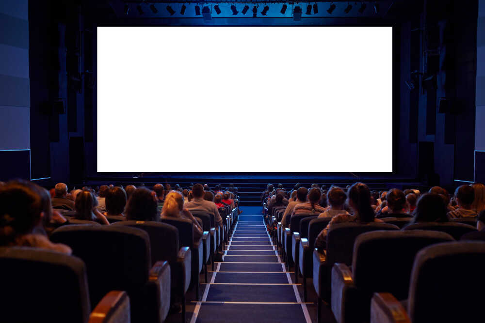 pełna sala kinowa z białym ekranem